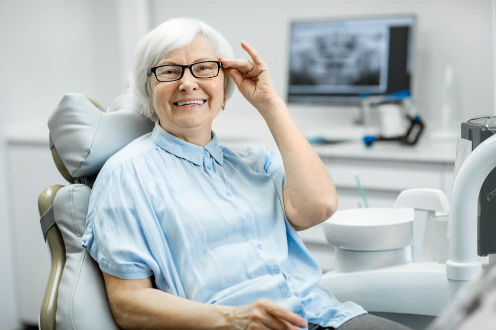 an old woman holding her specs and posing with a smile